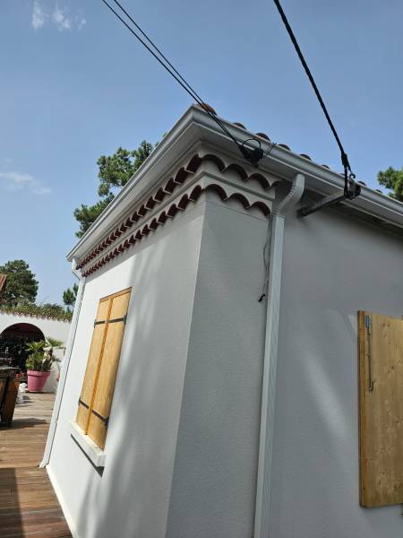 Installation de gouttières blanches avec descentes et parafeuilles sur une maison à Mimizan